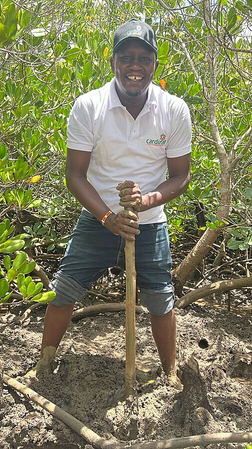 A CYA volunteer smiling while planting a mangrove seedling
